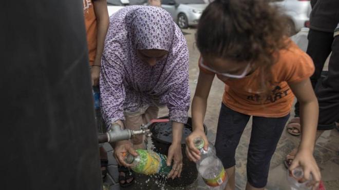 加沙南部居民周日在汗尤尼斯取水。