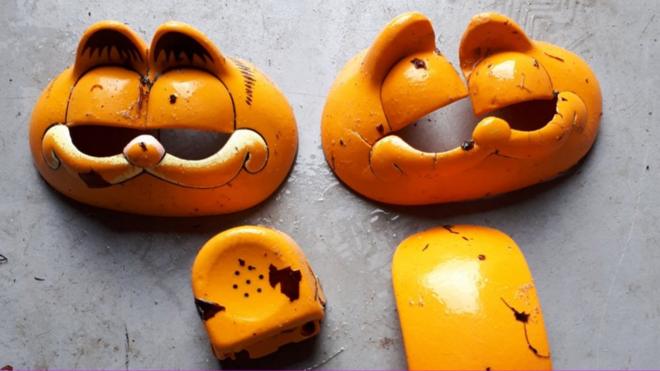 The plastic remnants of multiple Garfield phones - with vacant eye sockets starting from the face piece and a broken earpiece among them