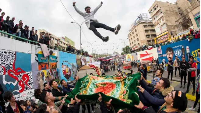 Nin da'yar oo ka mid ah dibedbaxayeyaasha dalkaasi Ciraaq oo ay kor u tuurayaan asxaabtiisa fagaaraha Taxriir kula mudaaharaadaysay.