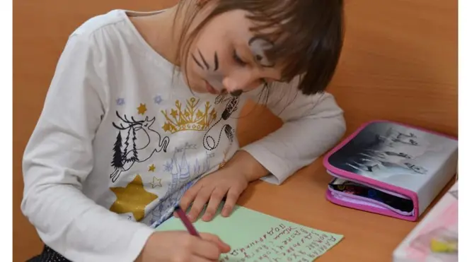 Діти переселенців підписують святкові листівки для літніх людей