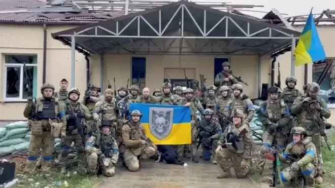 Ukrainian troops pose with flags in a village retaken from Russian control in the north-eastern Kharkiv region. Photo: 11 September 2022
