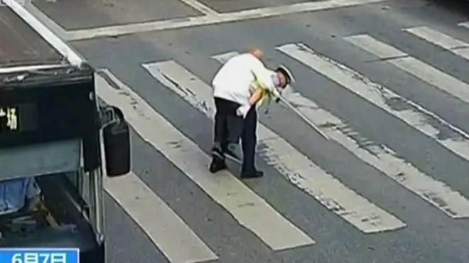 Полицајац помаже старијем човеку да пређе улицу