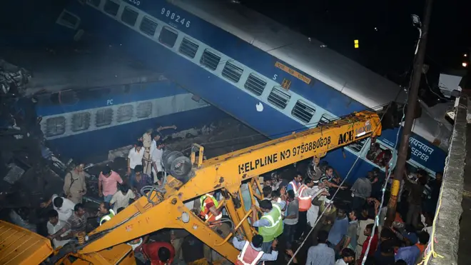 Emergency workers look for survivors on the wreckage of a train carriage after a train derailed in the Indian state of Uttar Pradesh on August 19, 2017