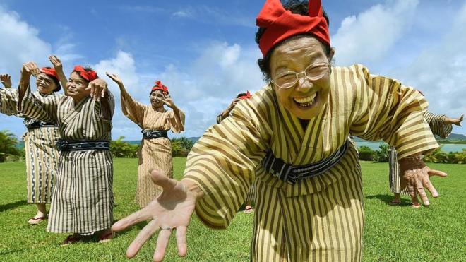 Unas ancianas cantan y bailan usando trajes tradicionales en Okinawa.