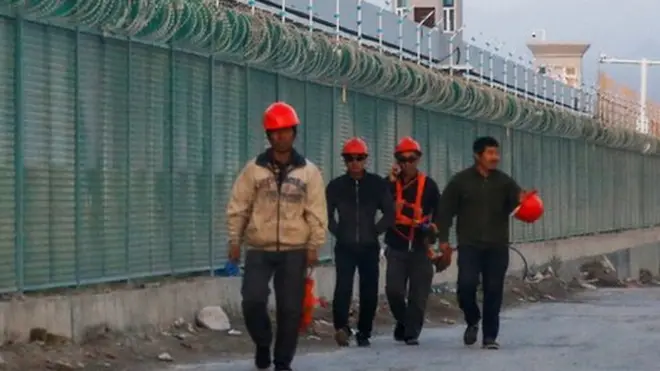 Pekerja berlajan di luar pagar tempat yang disebut secara resmi sebagai pusat pelatihan ketrampilan di Dabancheng di Xinjiang, September 2018.