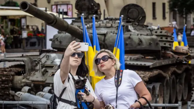 Dos mujeres se toman una foto con un tanque ruso capturado por las tropas ucranianas.
