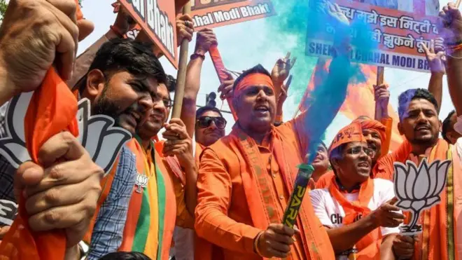Indian Bharatiya Janata Party (BJP) supporters hold colour smoke crackers as they celebrate on the vote results day for India's general election at BJP headquarters in New Delhi on May 23, 2019.