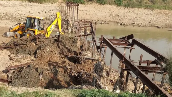 The earth excavator dismantling the bridge
