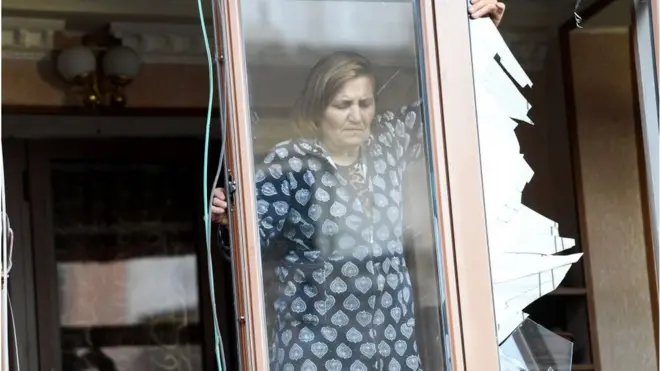 امرأة من مدينة ستيباناكيرت الرئيسية في منطقة ناغورنو كاراباخ تزيل الزجاج المتكسر من نافذة منزلها بسبب المعارك المسلحة