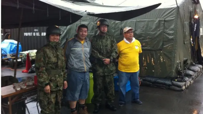 Miguel Kamiunten (de cinza), junto a militares nos abrigos após terremotosites de apostas esportivas no brasilTohokusites de apostas esportivas no brasil2011