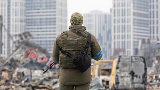 A soldier with a machine gun is on duty near the destroyed Retroville shopping centrv. Retroville shopping centre including its surrounding areas in Kyiv are destroyed after the Russian shelling attack