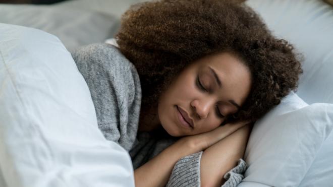 Imagem mostra mulher jovem dormindo numa cama