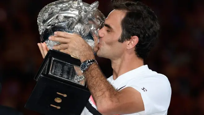 Roger Federer besa el trofeo que lo acredita como campeón del Abierto de Australia.