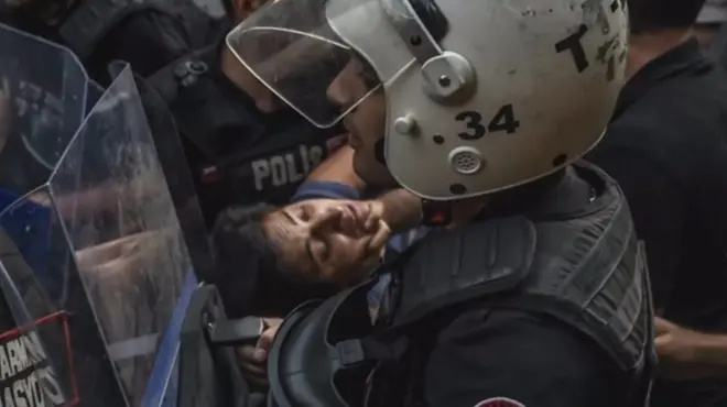 Jednog od radnika sa protesta nose policajci u punoj zaštitnoj opremi