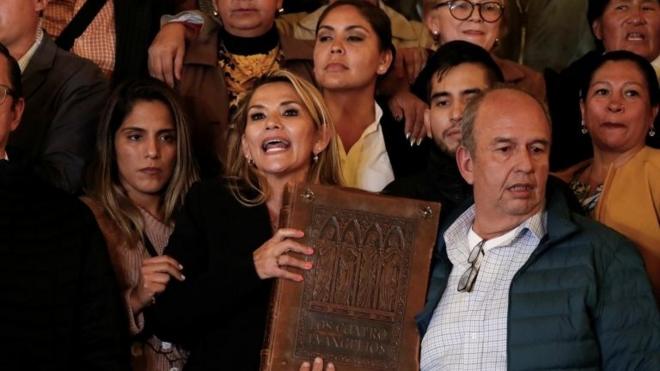 Áñez segura uma Bíblia, observada por outras pessoas