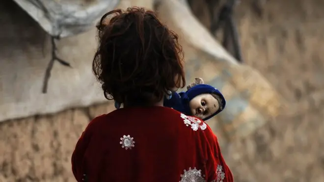 An Afghan girl holds a doll