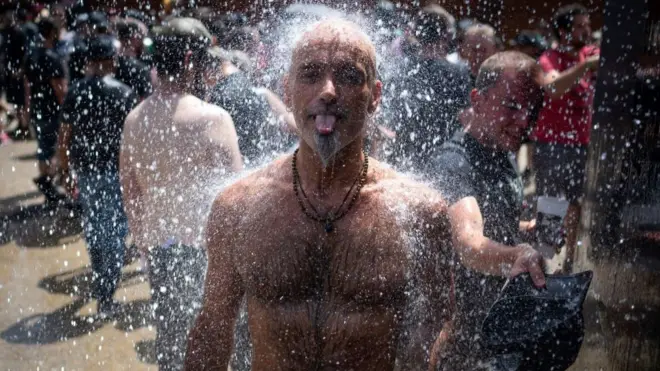 A heavy metal music fan cools off with water at a festival in Clisson, western France