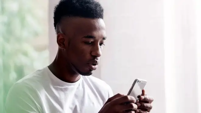 Un homme en train de manipuler son téléphone portable