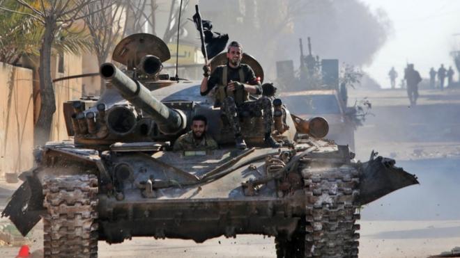 دبابة على متنها عدد من مقاتلي المعارضة السورية الذين تدعمهم تركيا في إدلب.