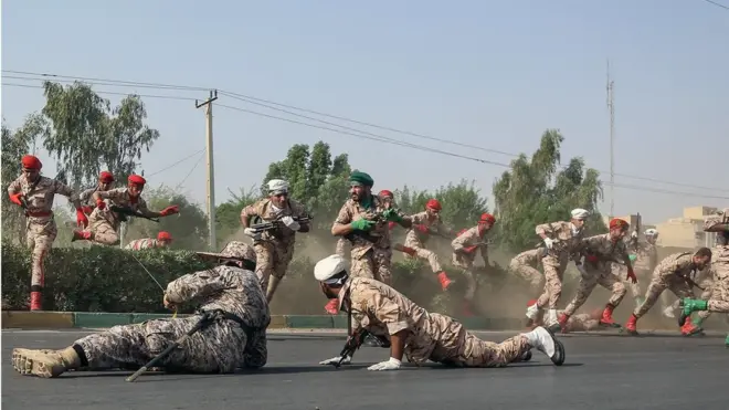 Iranian soldiers jump over a hedge at a street as they run for cover during a terror attack that occurred during a military parade in the city of Ahvaz, southwest Iran, 22 September 2018.