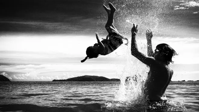 A father and daughter play together in the sea