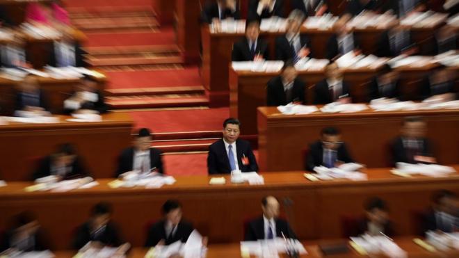 Chinese President Xi Jinping, centre and in focus, surrounded by delegates, out of focus, at a plenary session of the National People's Congress (NPC) at the Great Hall of the People in Beijing, Sunday, March 12, 2017.