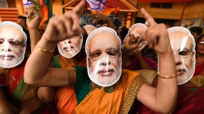 Indian Bharatiya Janata Party (BJP) supporters wearing masks of Indian Prime Minister Narendra Modi dance as they celebrate on the vote results day for India"s general election at BJP office in Guwahati on May 23, 2019