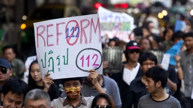 นักเคลื่อนไหวถือป้ายเรียกร้องให้ปฏิรูปกฎหมายอาญามาตรา 112 ของไทยในการเดินขบวนต่อต้านกฎหมายนี้ในกรุงเทพฯ เมื่อวันที่ 10 ธ.ค. 2554