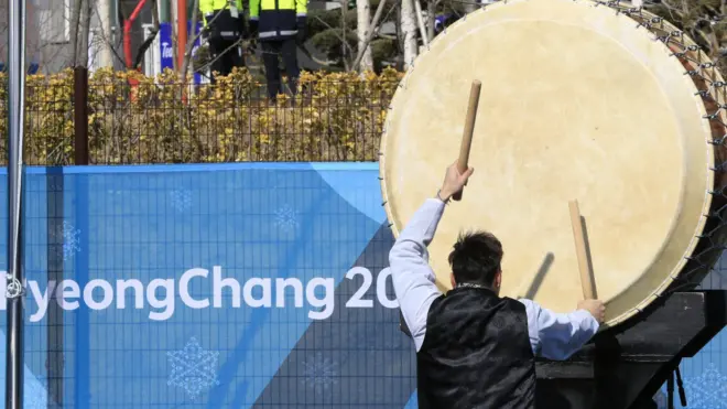 Барабанщик на фоне эмблемы игр