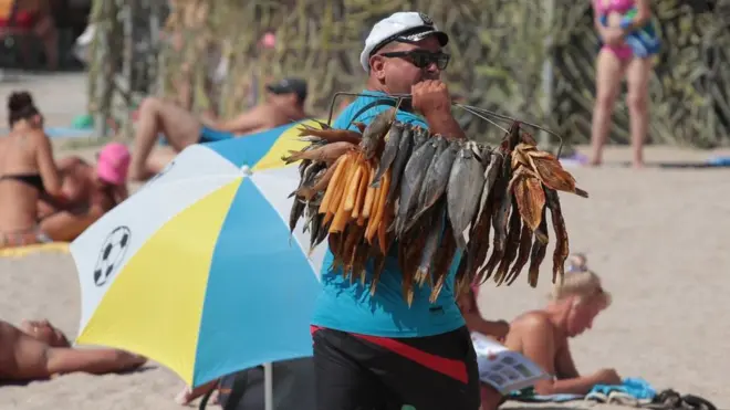 чоловік продає в'ялену рибу на пляжі