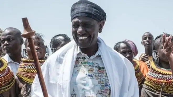 William Ruto (hagati) na Guverineri w'akarere ka Marsabit Mohamud Mohamed Ali (iburyo), bagenda n'amaguru bari kumwe n'ababyinnyi bo mu bwoko bwa Turkana, mu iserukiramuco ryo ku nshuro ya 11 ry'abo muri ubwo bwoko rya Marsabit Lake Turkana Culture Festival, i Loiyangalani, iruhande rw'ikiyaga cya Turkana, mu majyaruguru ya Kenya, ku itariki ya 28 y'ukwezi kwa gatandatu mu 2018