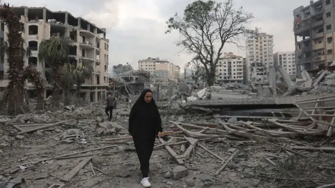 Seorang perempuan Palestina berjalan di kawasan Al-Rimal, Kota Gaza, yang hancur akibat gempuran udara Israel, pada 10 Oktober 2023.