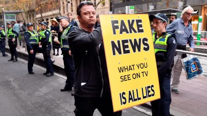 شاب يحمل لوحة لرفض الأخبار الكاذبة