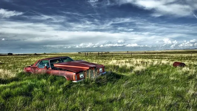 एक खुले मैदान में बेकार पड़ी कार