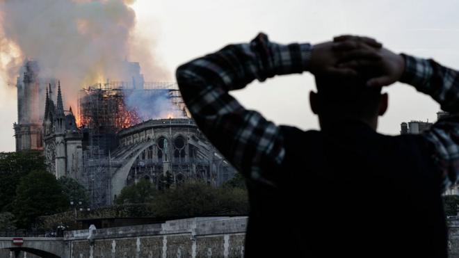 Очевидец наблюдает за пожаром в соборе Парижской богоматери
