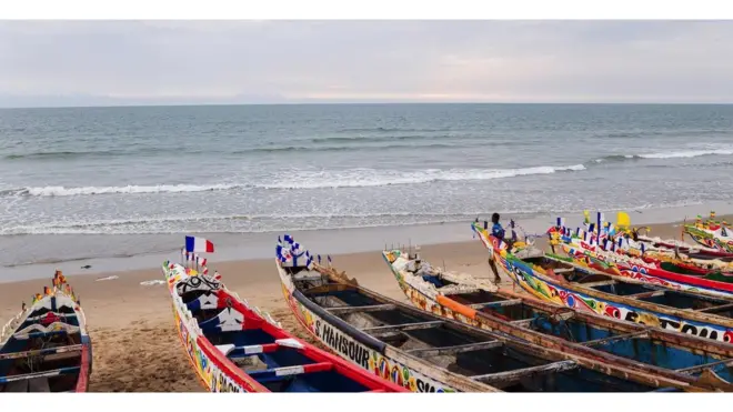 Plage avec une large vue sur l'océan Atlantique, avec des bateaux à l'eau au premier plan.