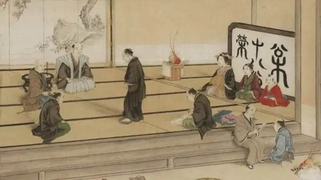 Seorang pria melangkah ke fumie, disaksikan para pejabat.