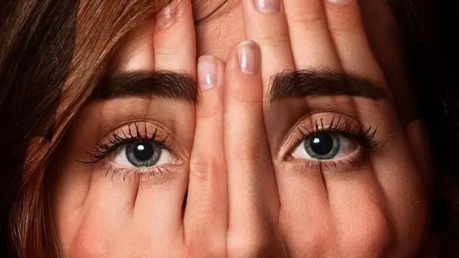 Una imagen de un rostro de mujer con las manos superpuestas