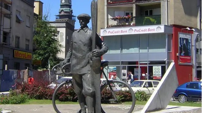 Spomenik Ivanu Sariću u Subotici - u jednoj ruci drži bicikl, a u drugoj elisu aviona
