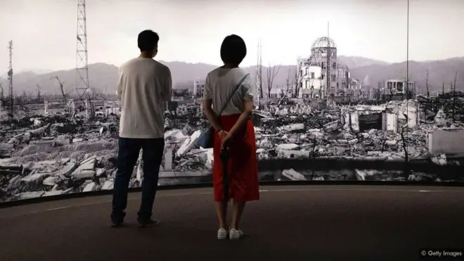 dvoje ljudi ispred slike rusevina