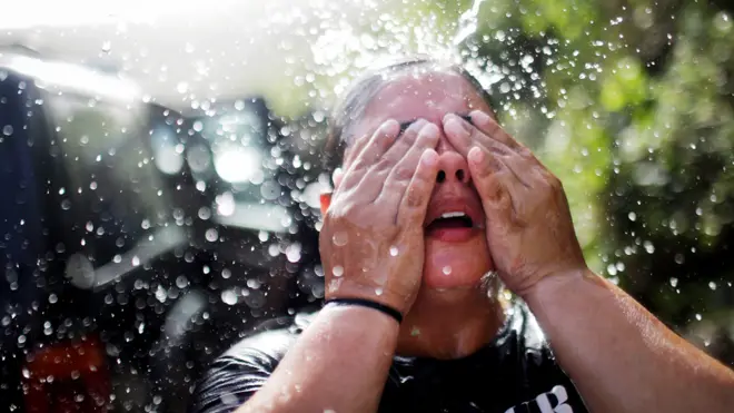 Una mujer en Puerto Rico se refresca tras llenar recipientes debido a la escasez de agua luego del huracán María. La temporada de huracanes del Atlántico fue la más activa desde 2005, una de las anomalías apuntadas en el informe Estados del Clima.