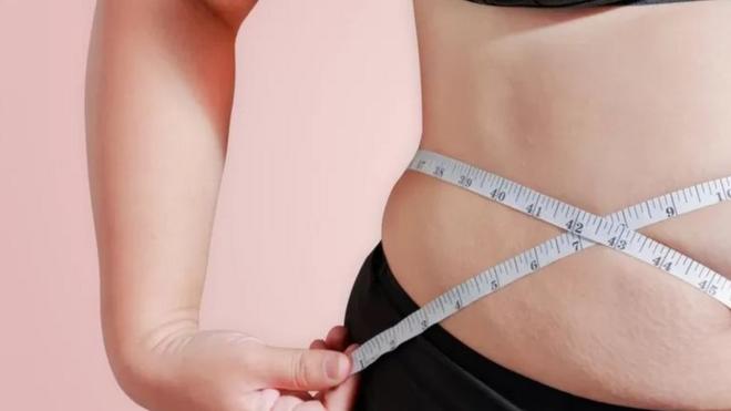Pessoa com sobrepeso mede a própria barriga