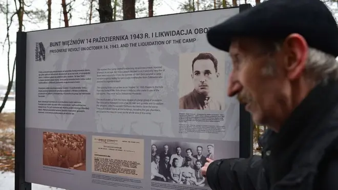 Seorang pria menunjuk papan penanda di lokasi bekas kamp pemusnahan Nazi di Sobibor, Polandia, 27 Januari 2016