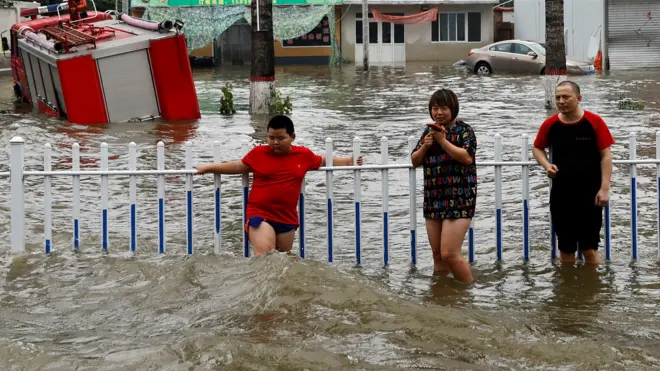 People stand by a rail amid floodwaters after the rains and floods brought by remnants of Typhoon Doksuri, in Zhuozhou, Hebei province, China August 3, 2023.