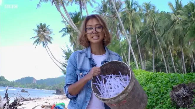 ผู้หญิงถือถังใส่หลอดพลาสติก