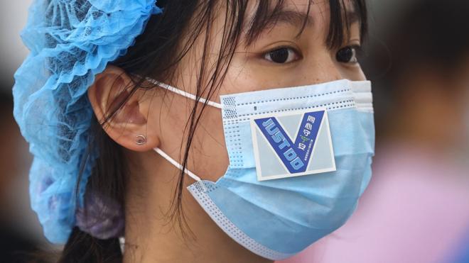 江蘇省南京市浦口區一處核酸檢測點內志願者口罩上貼著鼓勁用的貼紙（中新社圖片29/7/2021）