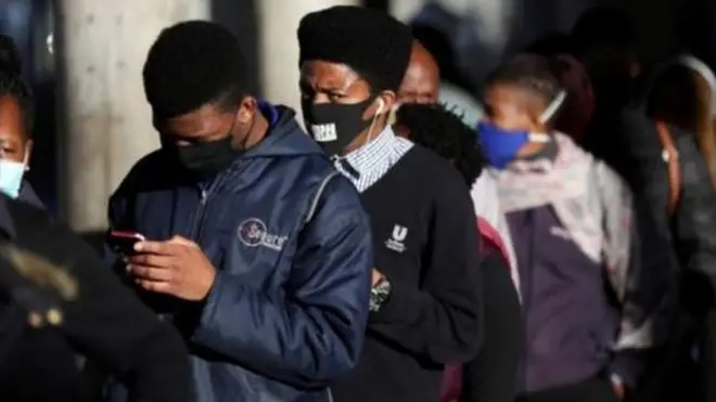 Des jeunes dans une queue, avec leurs masques