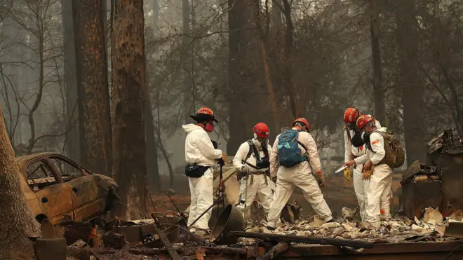 Rescue workers search for human remains at a home that was burned by the Camp Fire