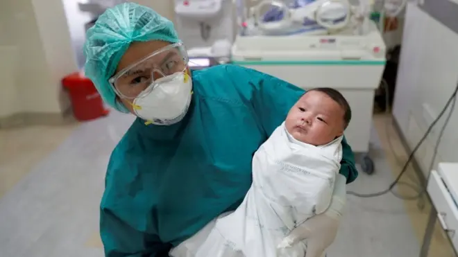 Seorang perawat menggendong bayi berusia satu bulan yang pulih dari Covid-19 di Bangkok, Thailand.