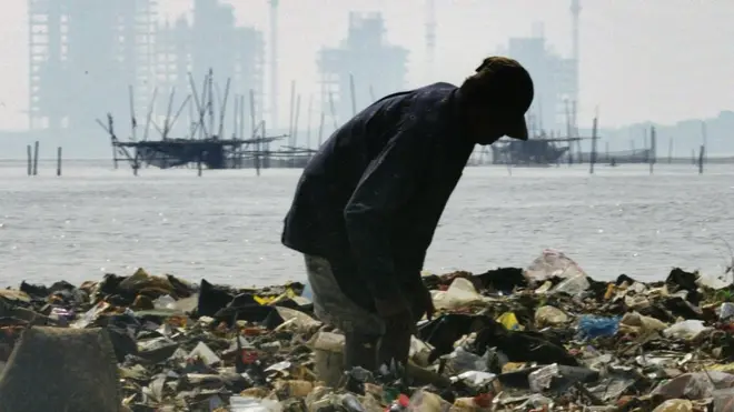 Seorang pemulung tengah mencari sampah di pantai Jakarta.